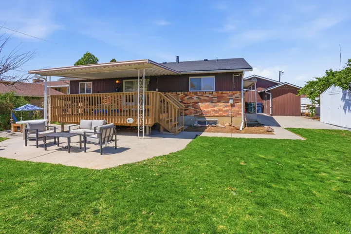 Back of property with a patio area, an outdoor hangout area, brick siding, a lawn, and a shed