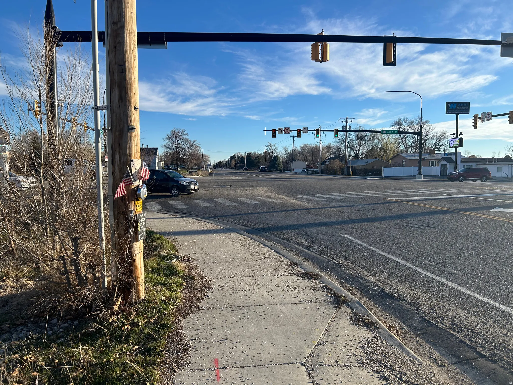 View of asphalt street with traffic lights, sidewalks, traffic signs, and curbs