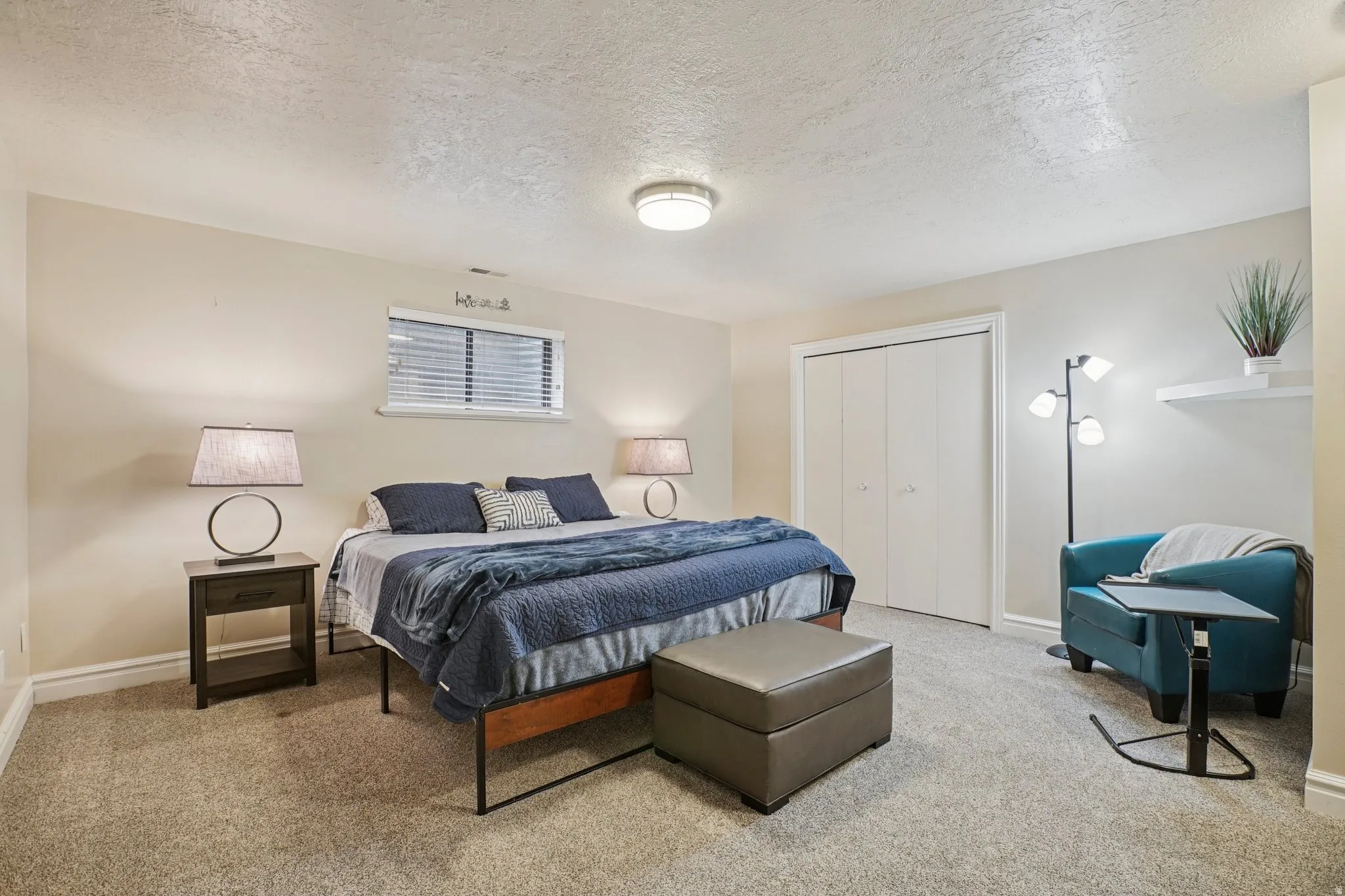 Carpeted bedroom featuring a textured ceiling and a closet