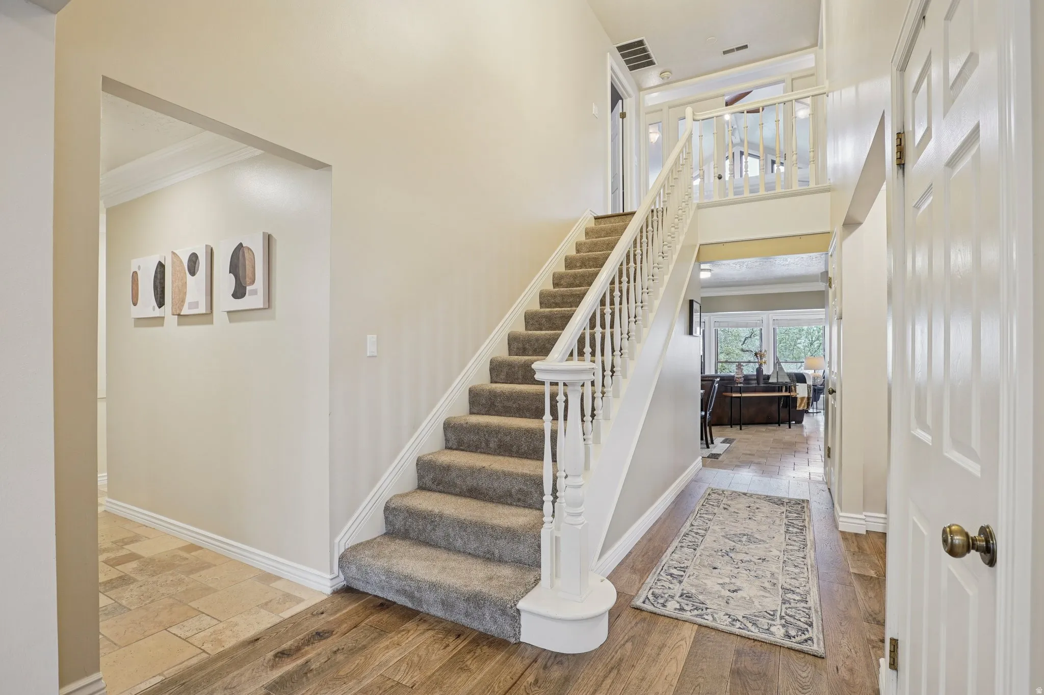 Stairs featuring crown molding, wood finished floors, and a high ceiling