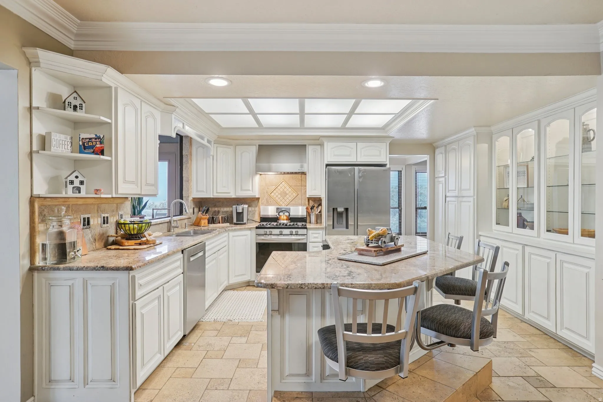 Kitchen with light stone counters, white cabinetry, a breakfast bar, decorative backsplash, and recessed lighting