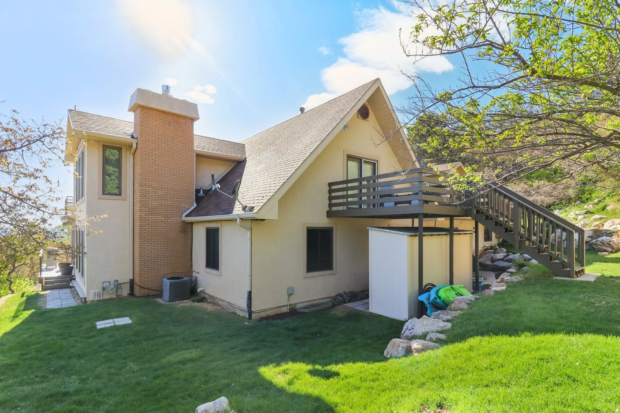 Back of house featuring stucco siding, a chimney, a yard, and roof with shingles