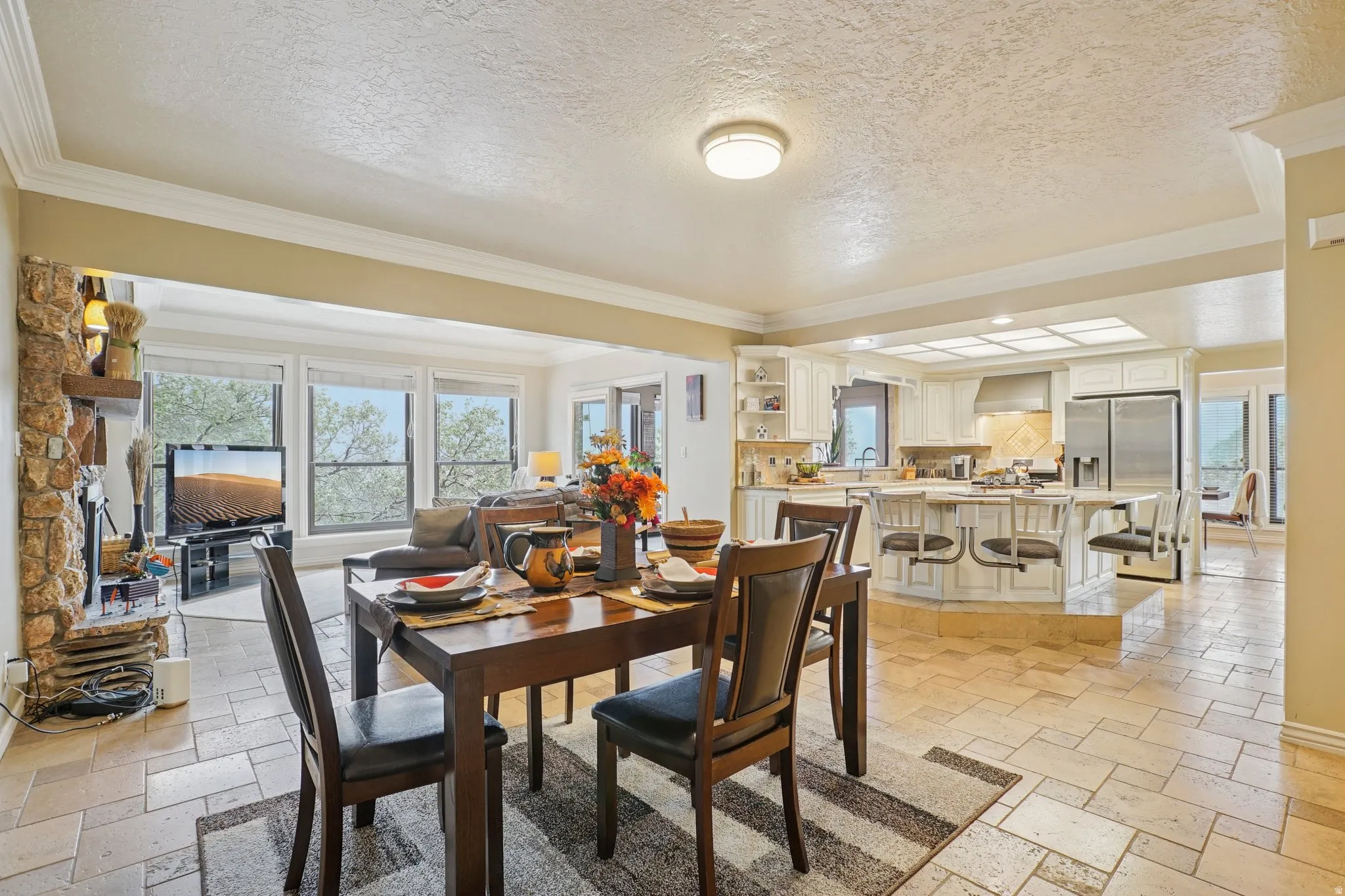 Dining space featuring stone tile flooring, a textured ceiling, and crown molding