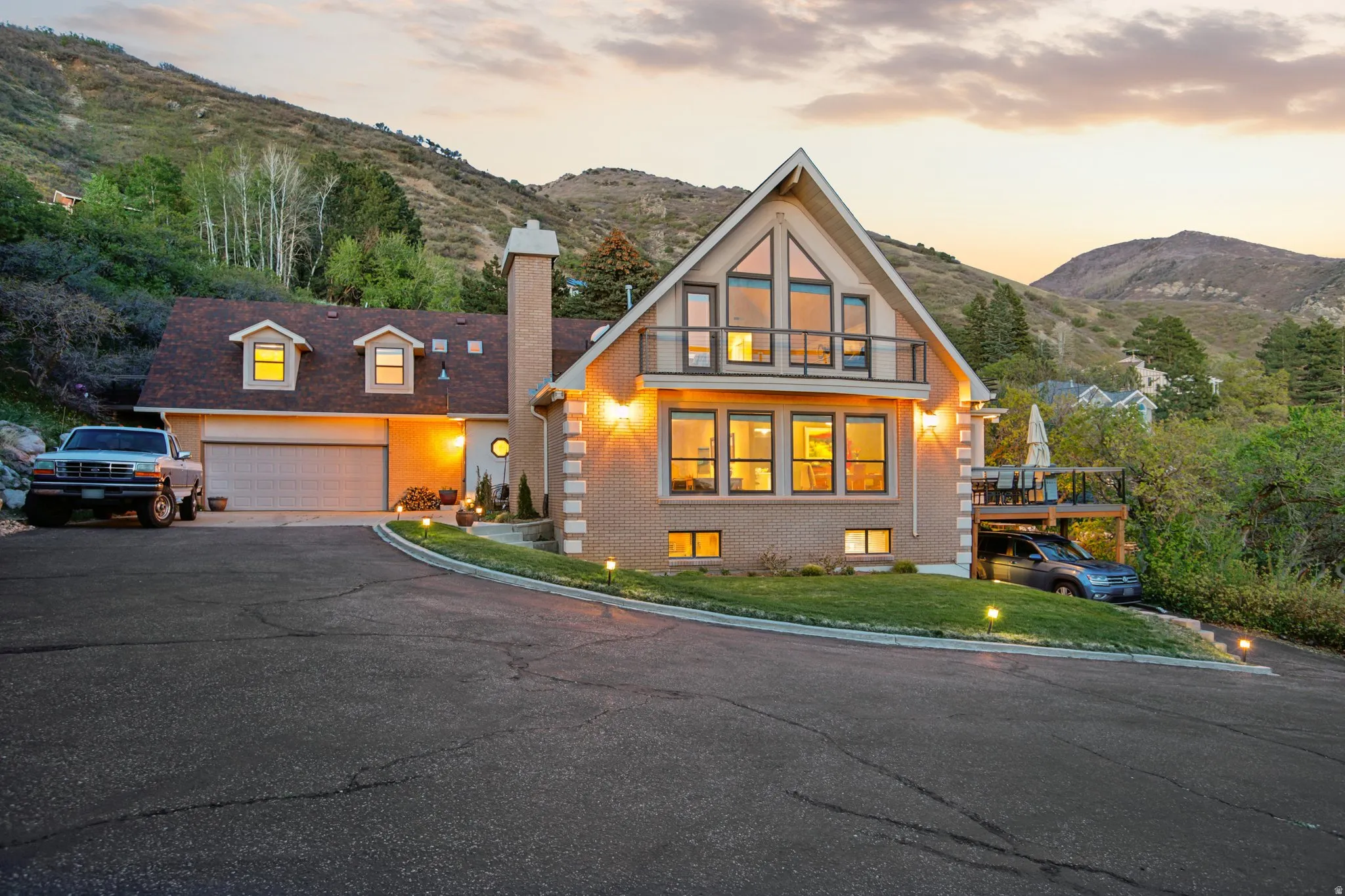 View of front of house featuring brick siding, a mountain view, a chimney, an attached garage, and driveway