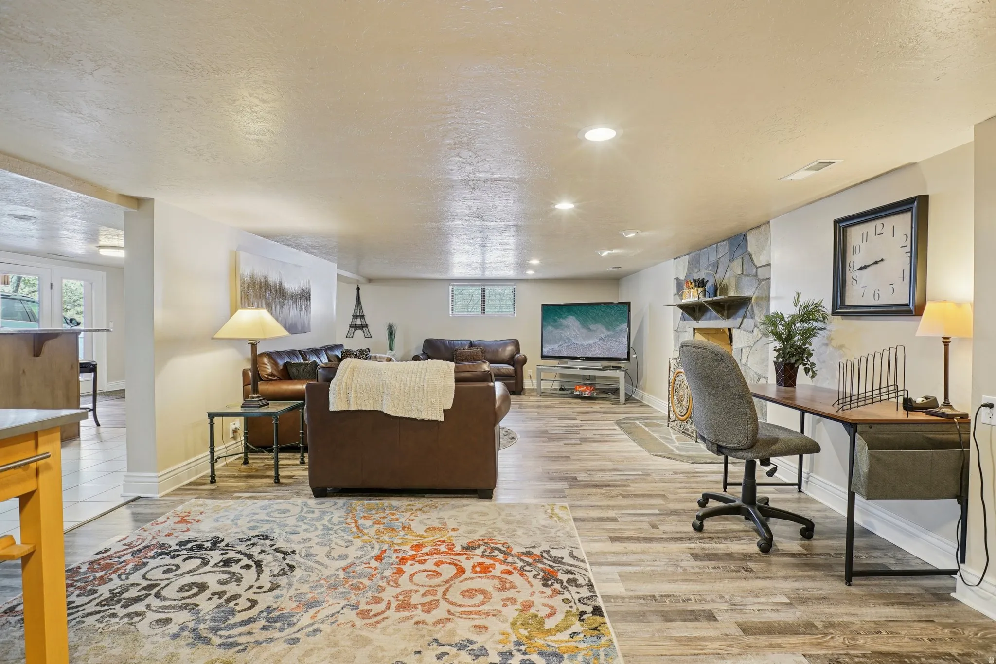 Living room with a textured ceiling, light wood-style floors, and recessed lighting