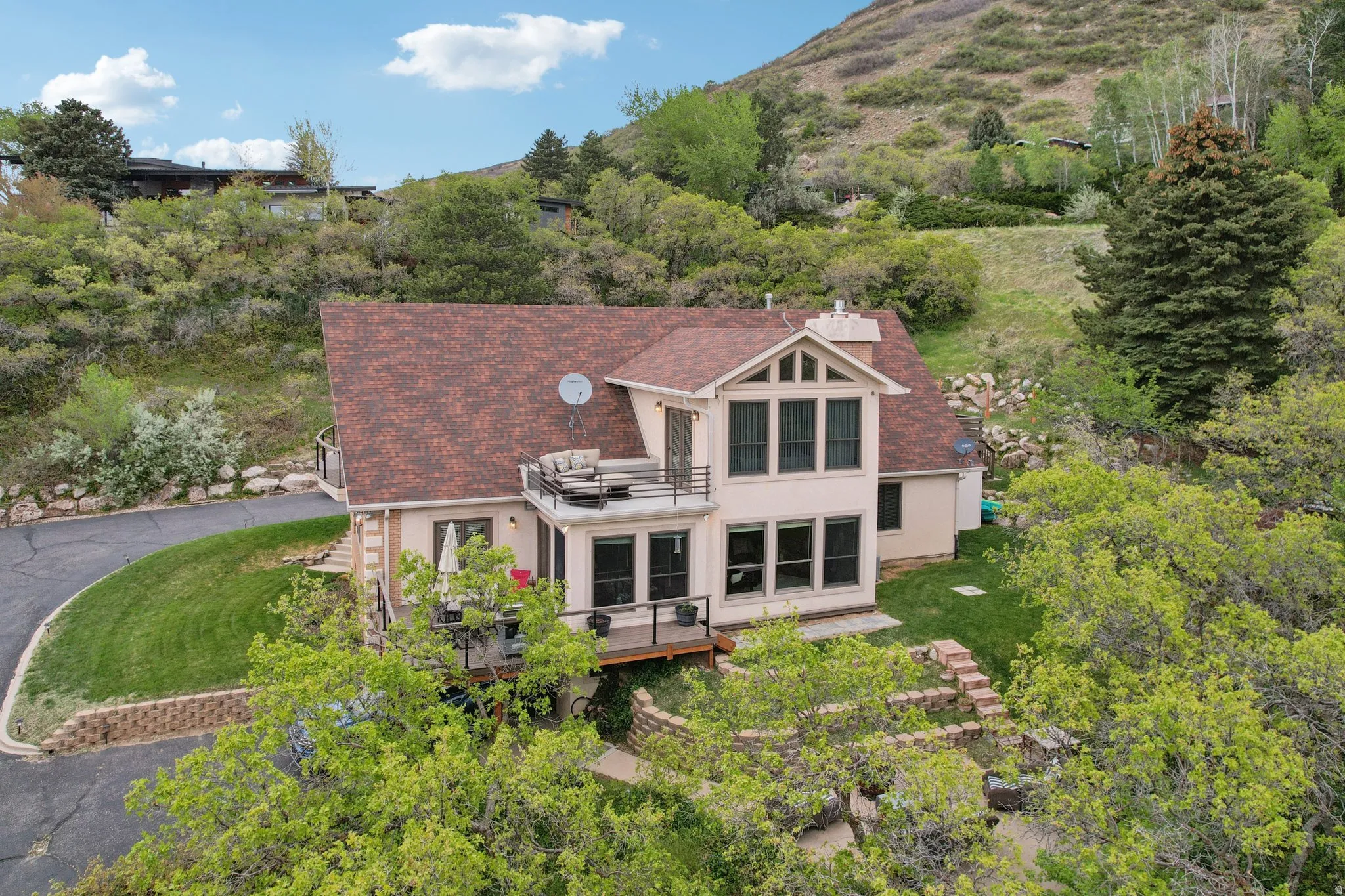 Rear view of house with stucco siding, roof with shingles, a deck with mountain view, and a yard