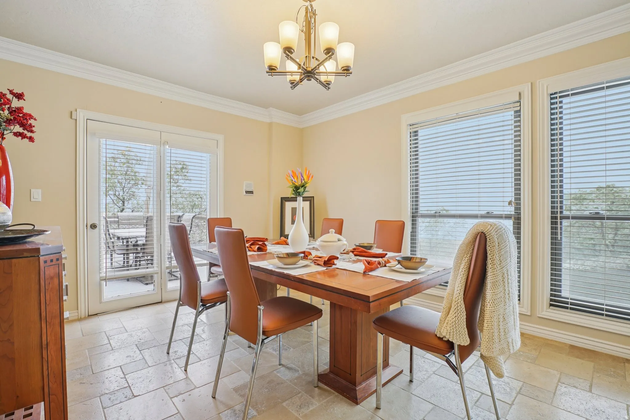 Dining space featuring stone tile floors, a chandelier, and ornamental molding