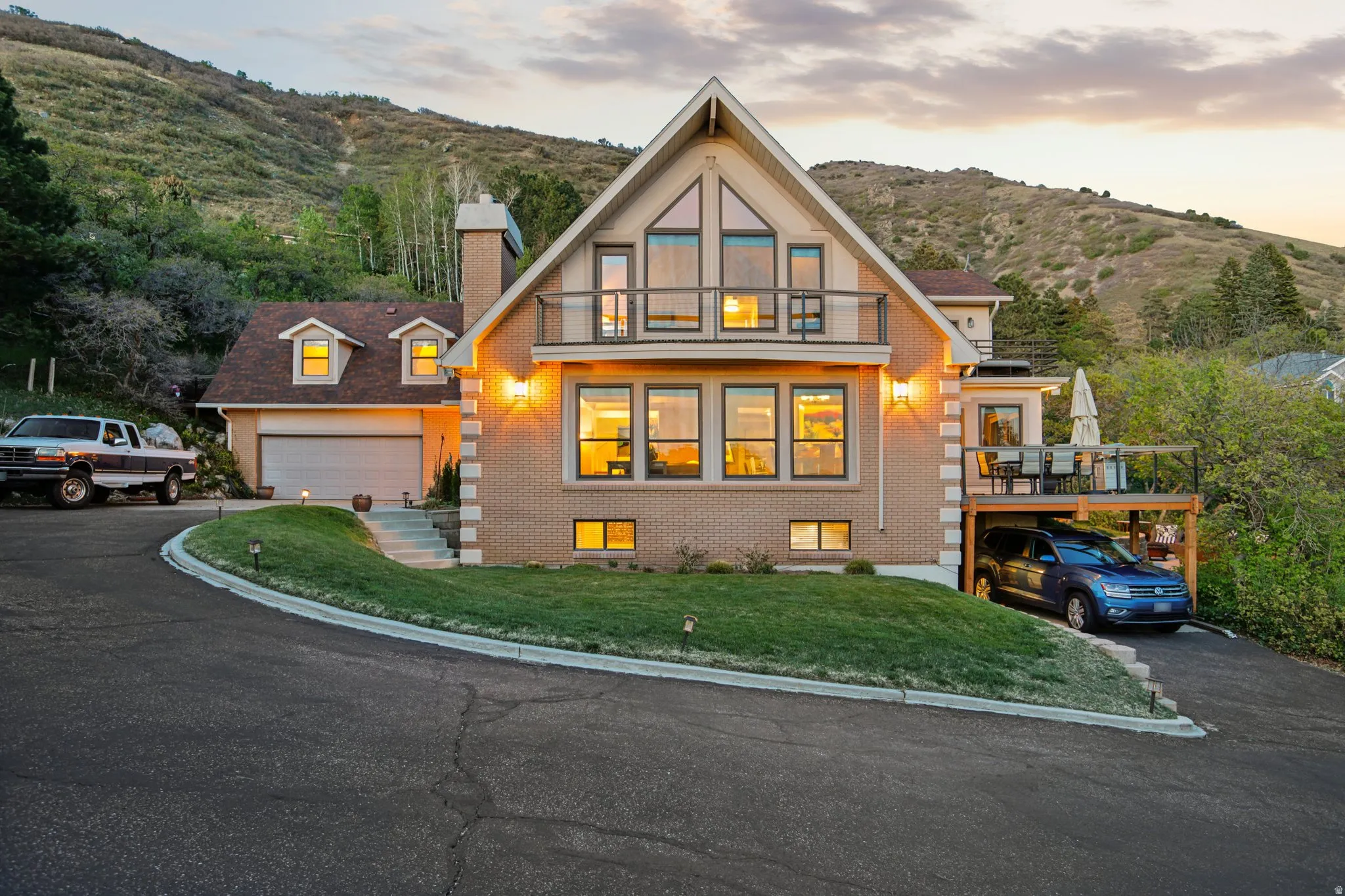 View of front of house with asphalt driveway, a chimney, brick siding, and a mountain view