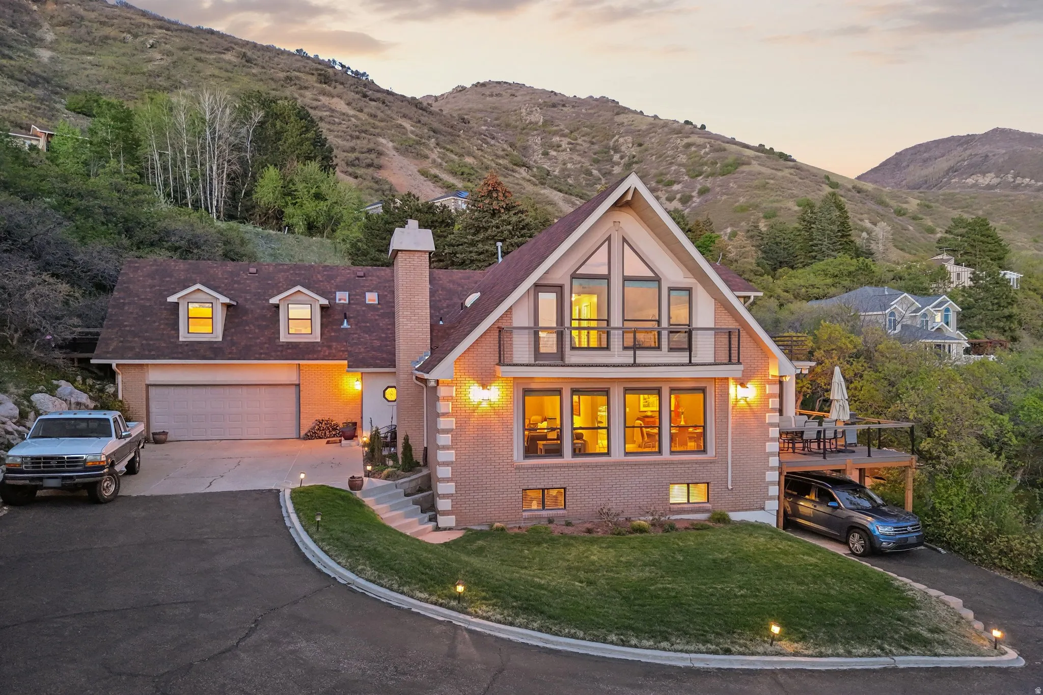 Tudor house featuring brick siding, asphalt driveway, a chimney, and a mountain view