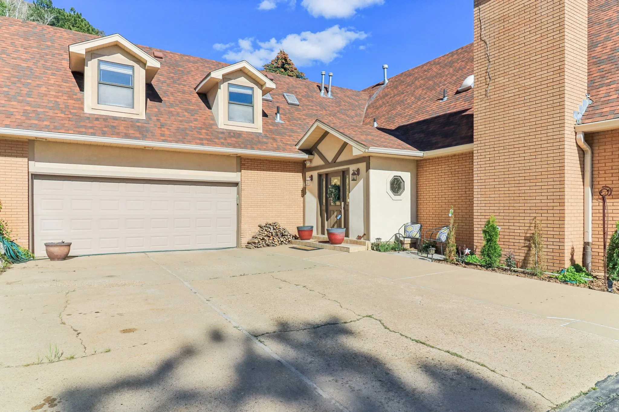 View of front of property with a shingled roof, driveway, and brick siding