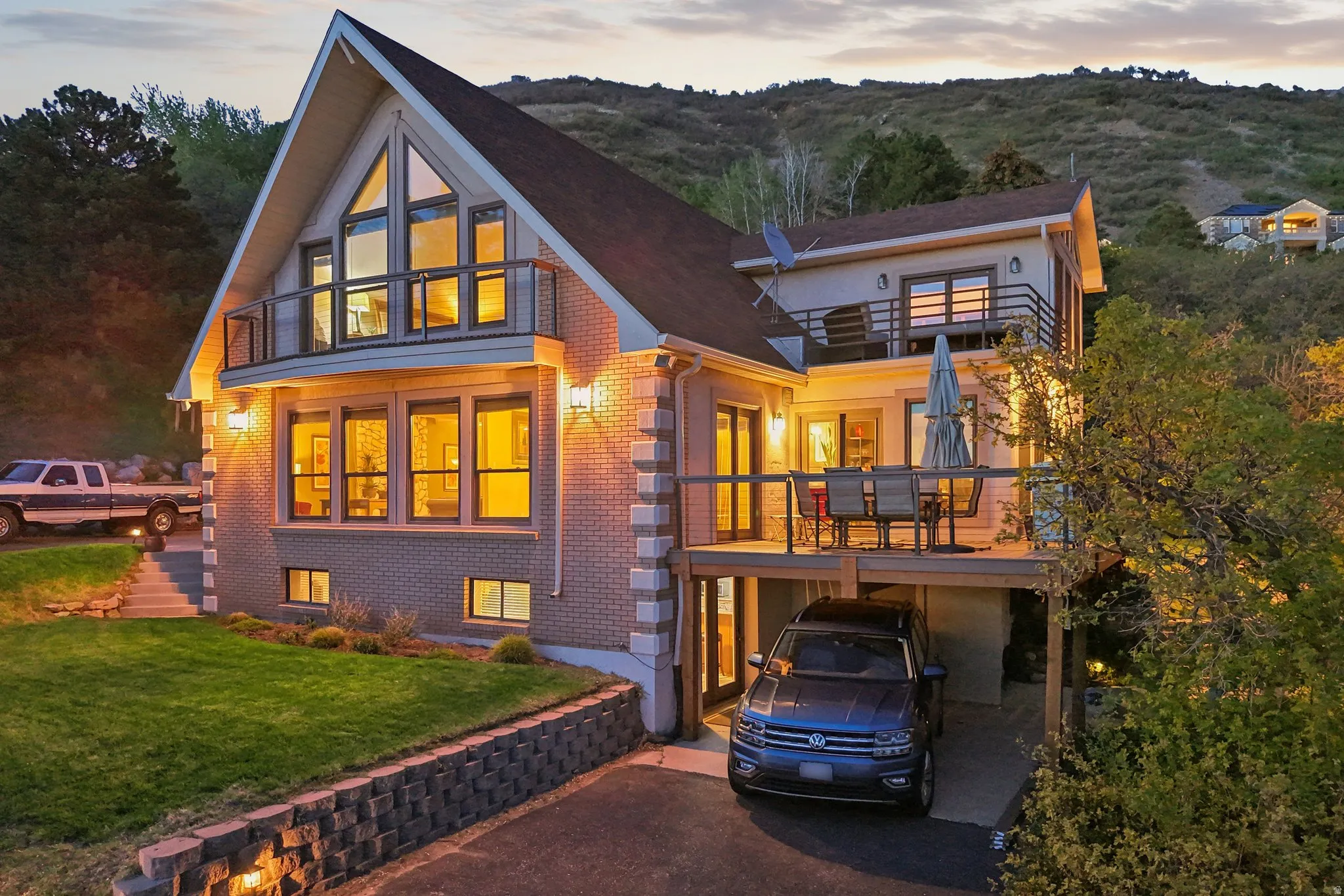 View of front of property featuring a balcony, brick siding, driveway, a front lawn, and a carport