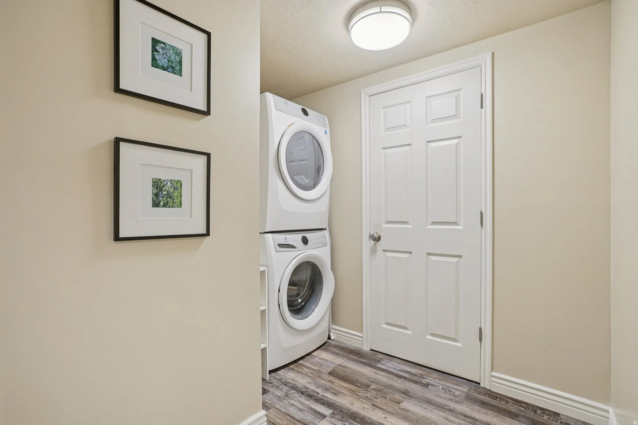 Laundry area featuring stacked washer / dryer and light wood-style flooring