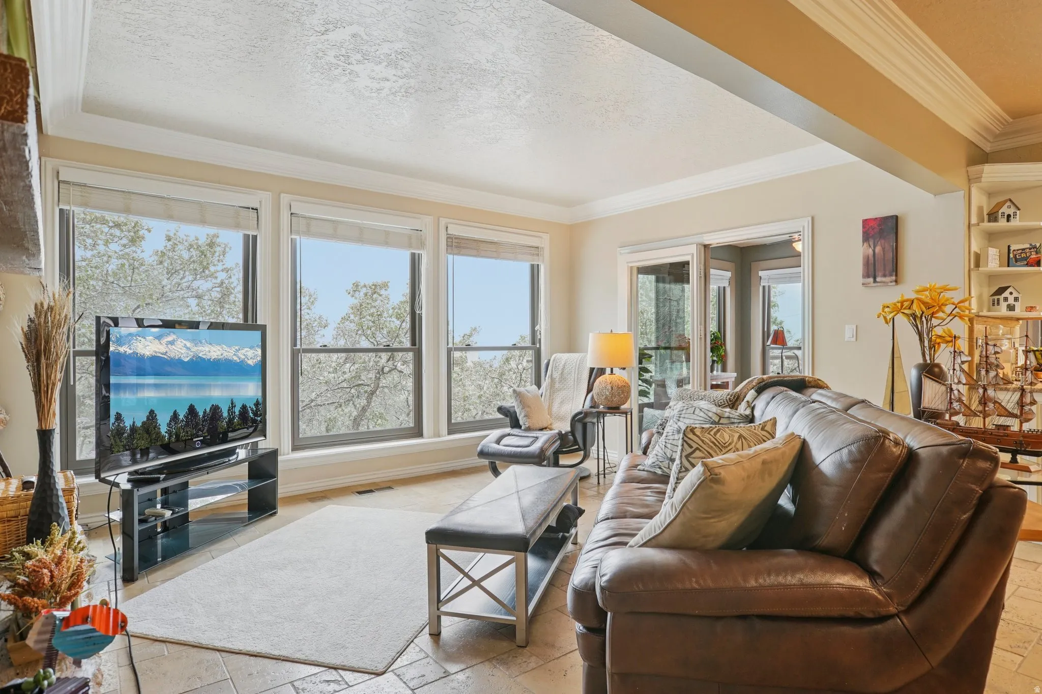 Living area with stone tile flooring, ornamental molding, and a textured ceiling