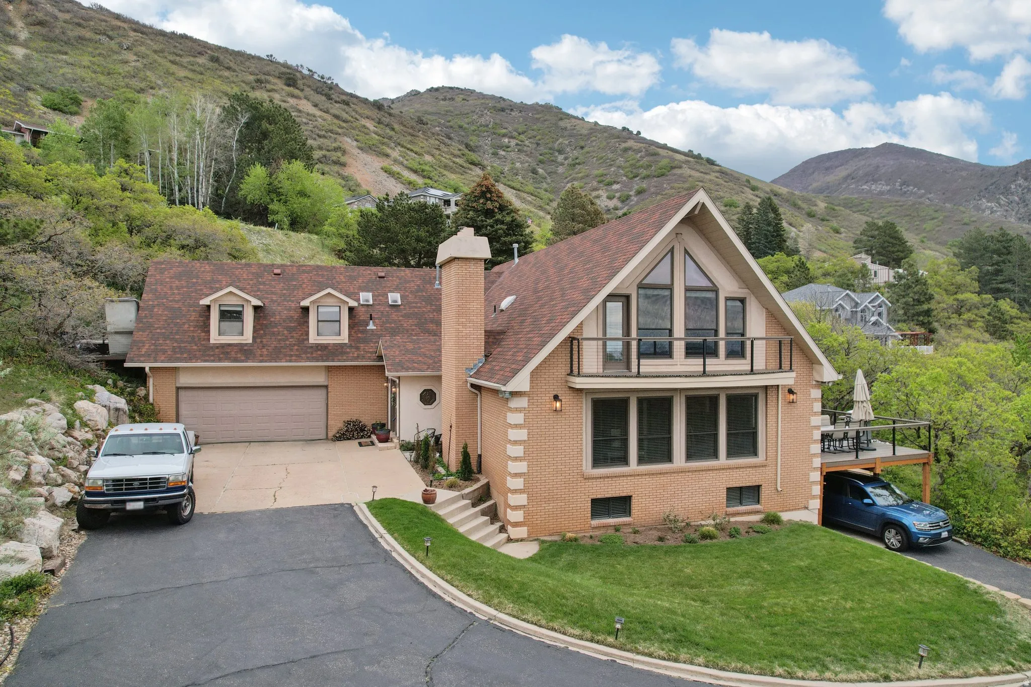 View of front of home featuring brick siding, a chimney, a mountain view, and driveway