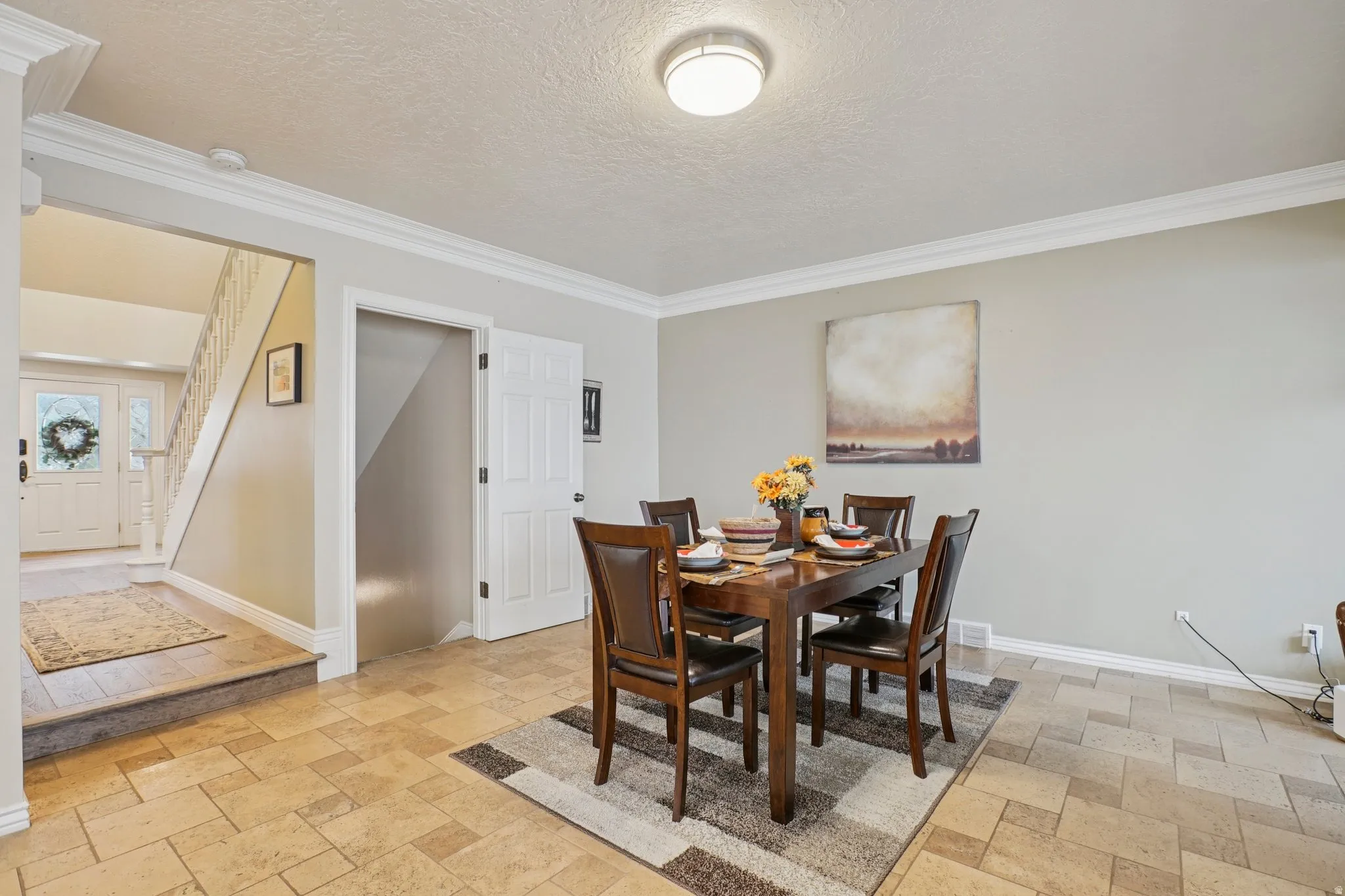 Dining space with crown molding, a textured ceiling, and stone tile flooring