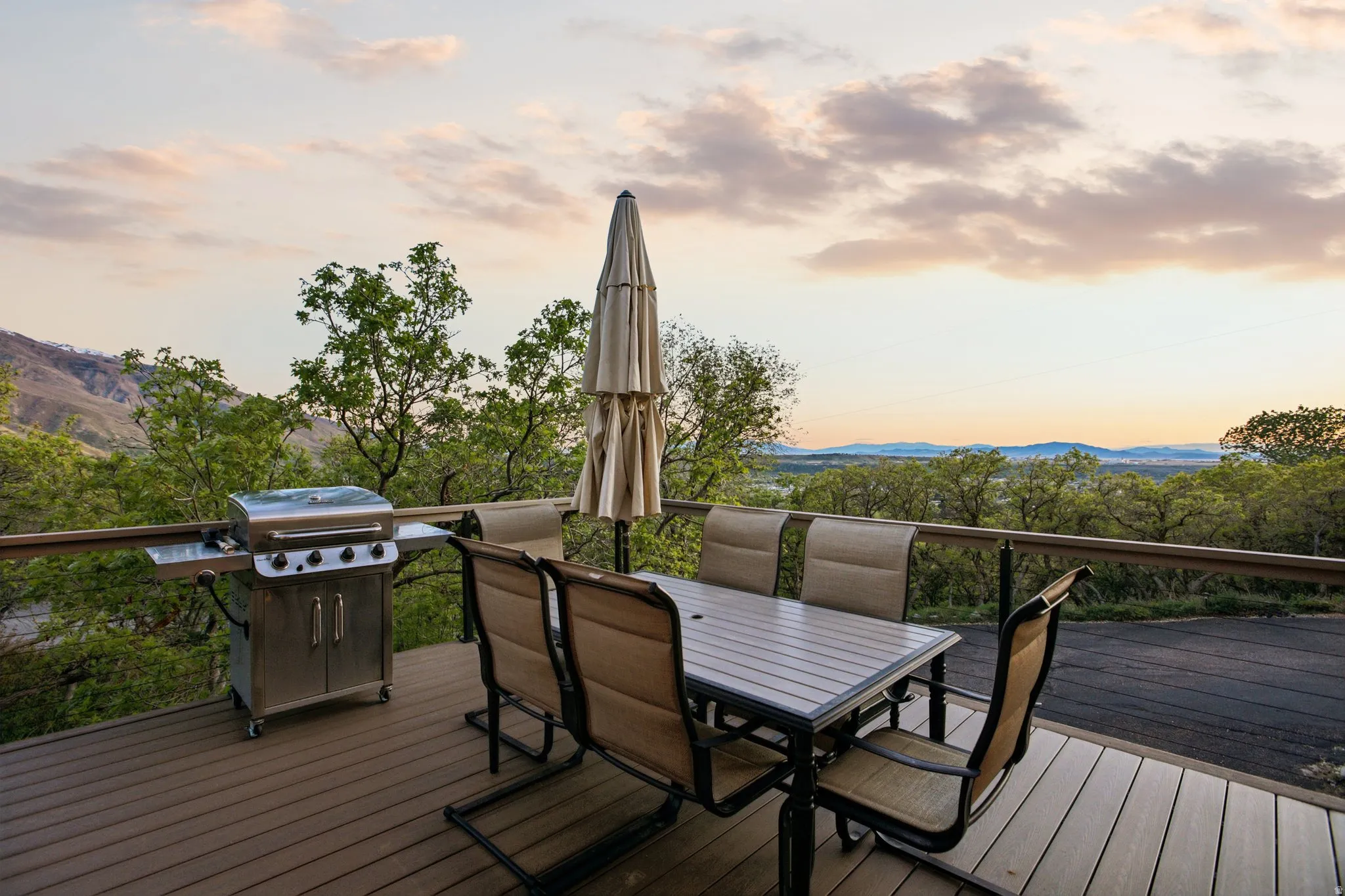 Deck at dusk with grilling area, outdoor dining area, and a mountain view