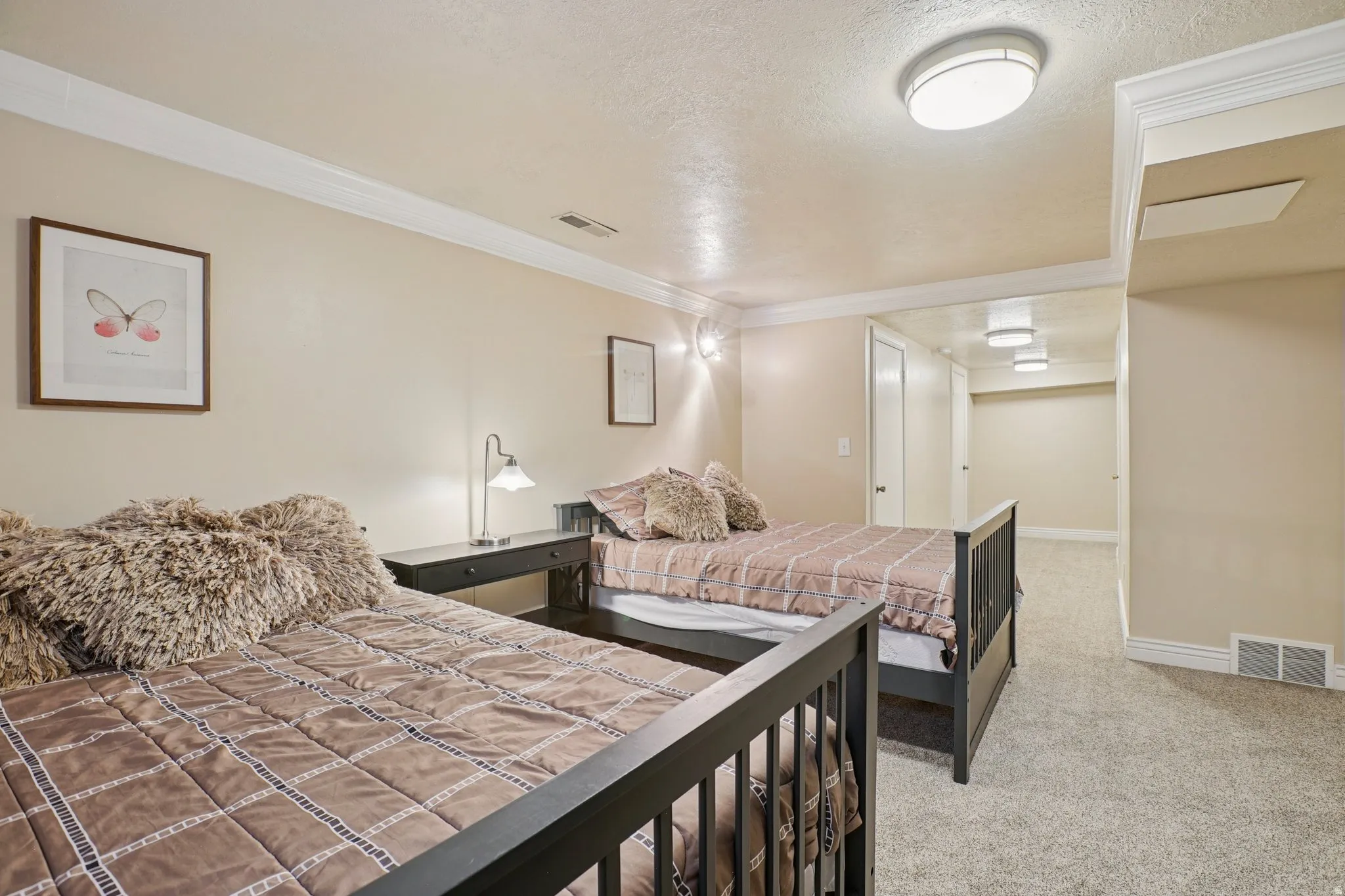 Bedroom with light carpet, a textured ceiling, and ornamental molding