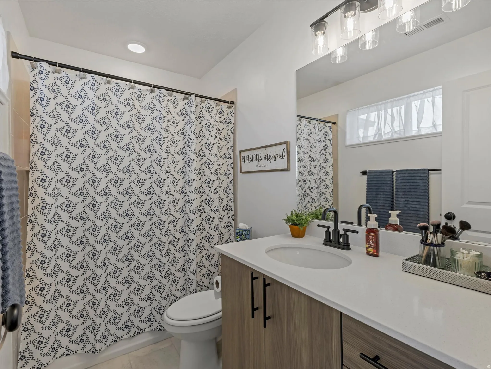 Full bath featuring vanity, curtained shower, and light tile patterned flooring
