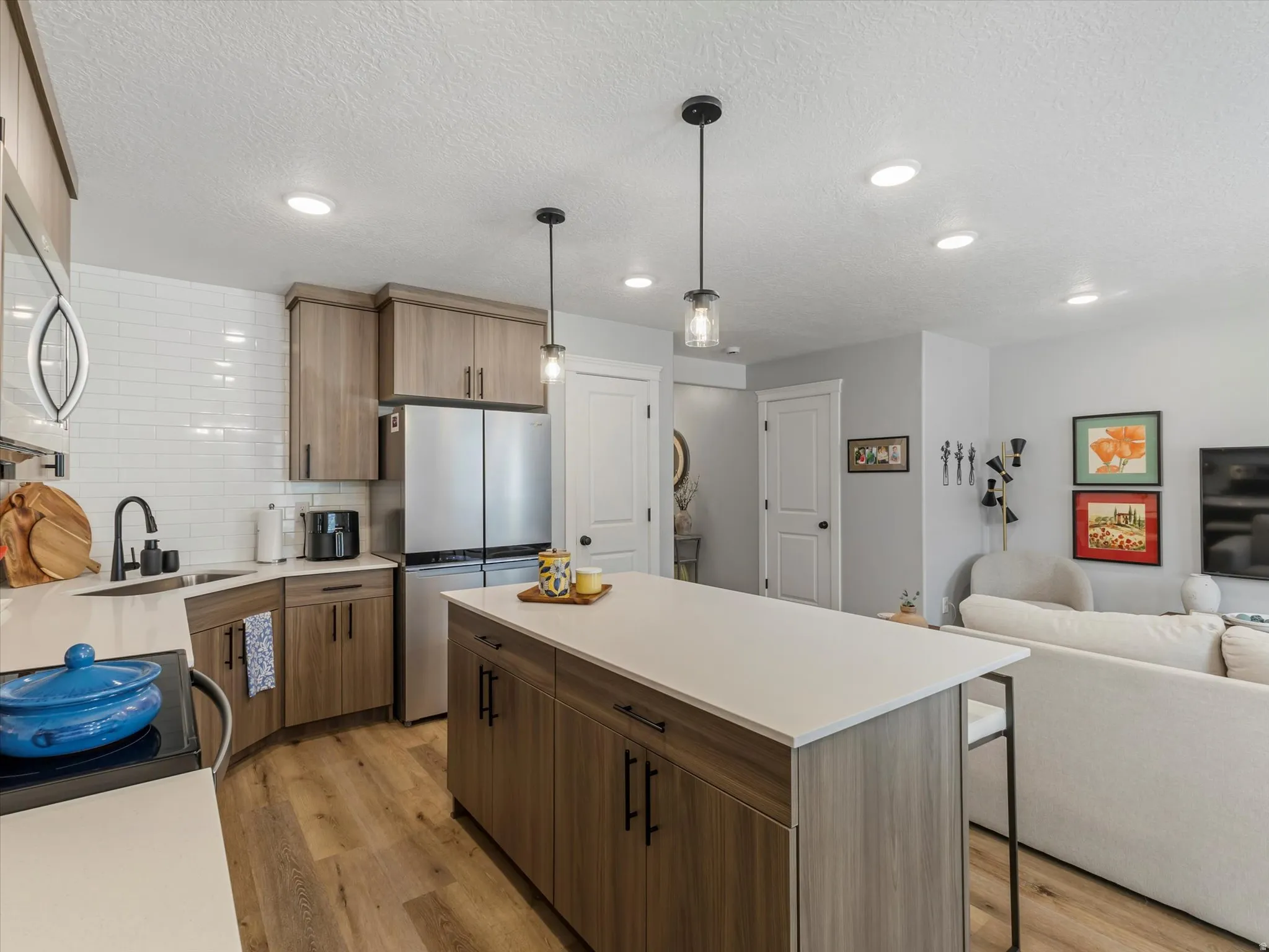 Kitchen featuring a center island, stainless steel appliances, pendant lighting, light wood finished floors, and open floor plan