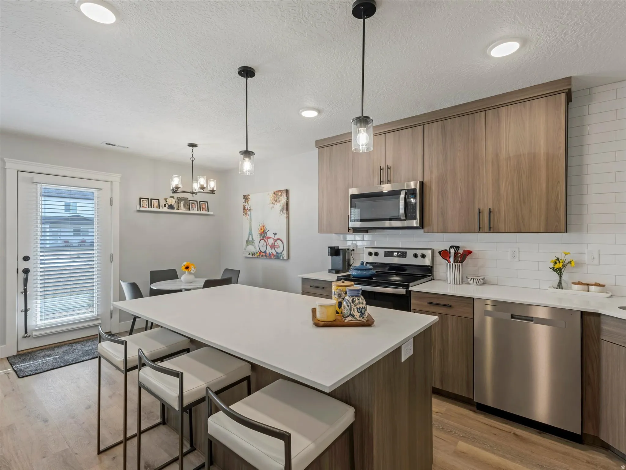 Kitchen with stainless steel appliances, tasteful backsplash, a kitchen breakfast bar, a center island, and light wood finished floors