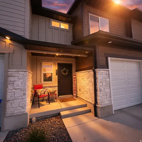 Entrance to property with board and batten siding, stone siding, a porch, and a garage