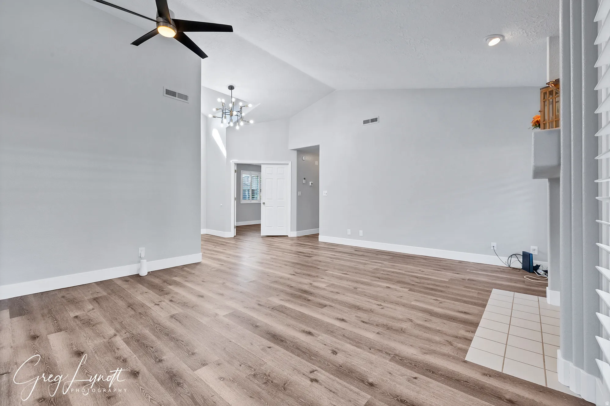 Unfurnished living room with lofted ceiling, light wood-style floors, ceiling fan, and suspended lighting