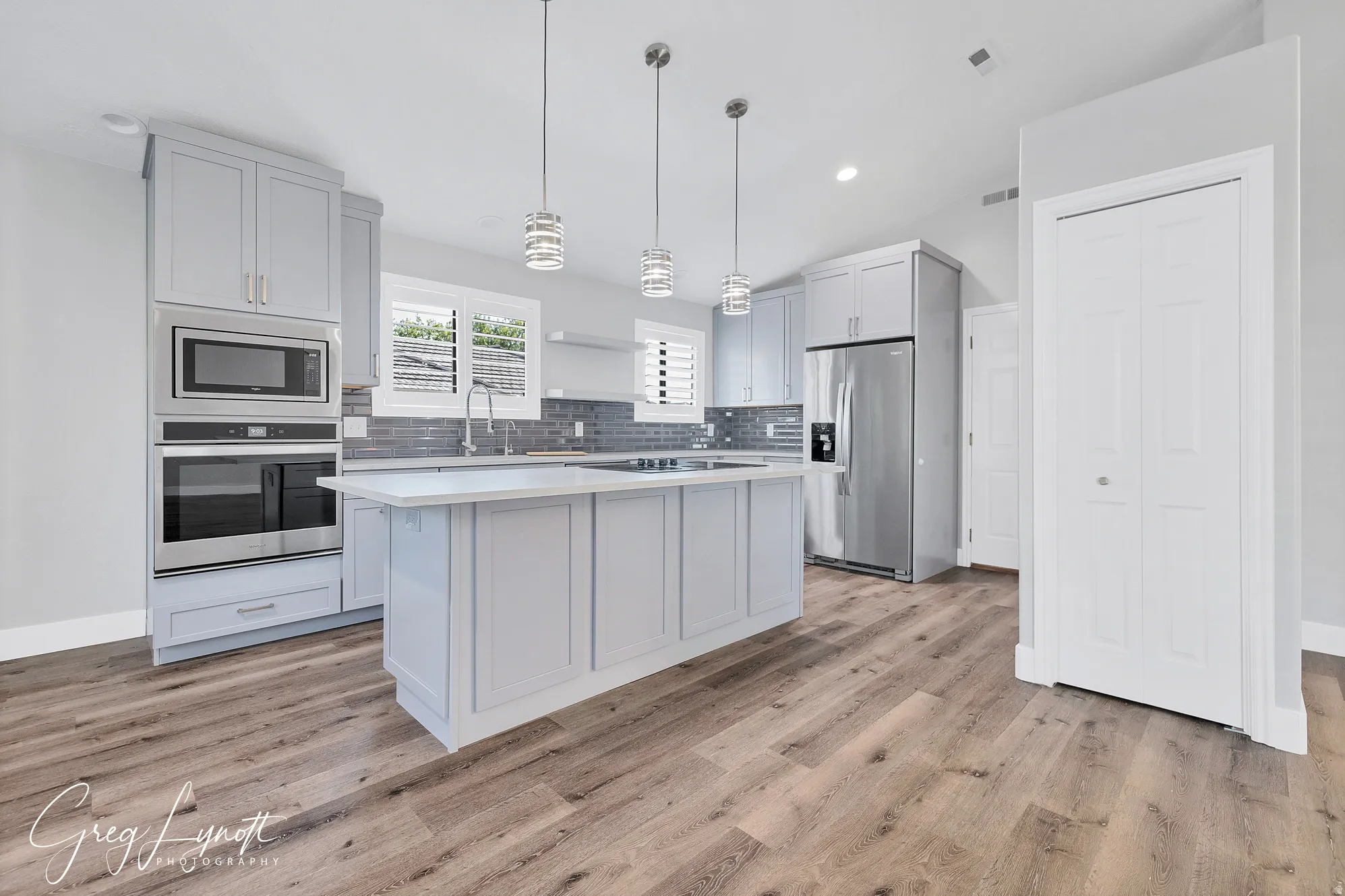 Kitchen with stainless steel appliances, pendant lighting, a center island, backsplash, and light wood-type flooring