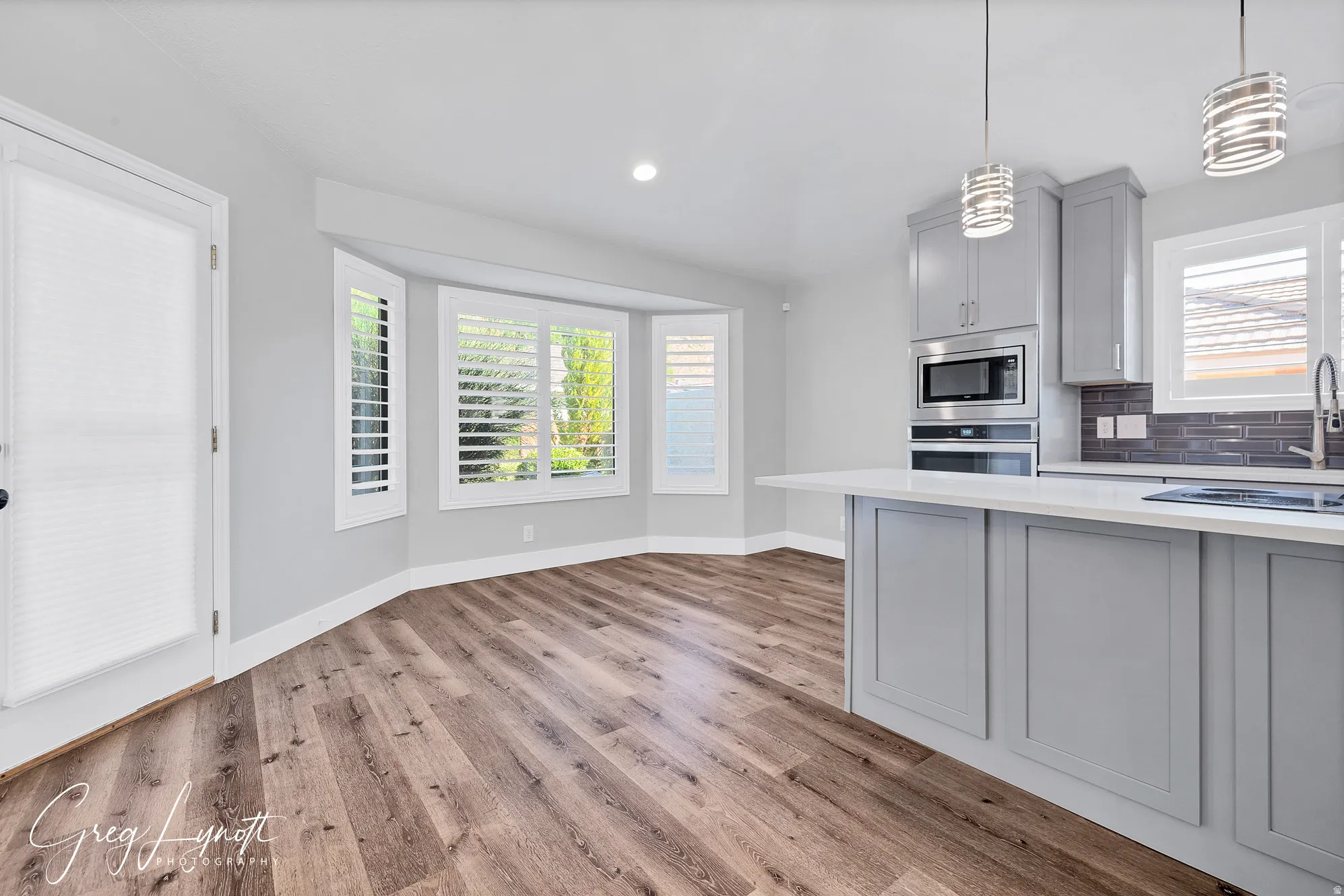 Kitchen with gray cabinetry, backsplash, light wood-style floors, and stainless steel appliances