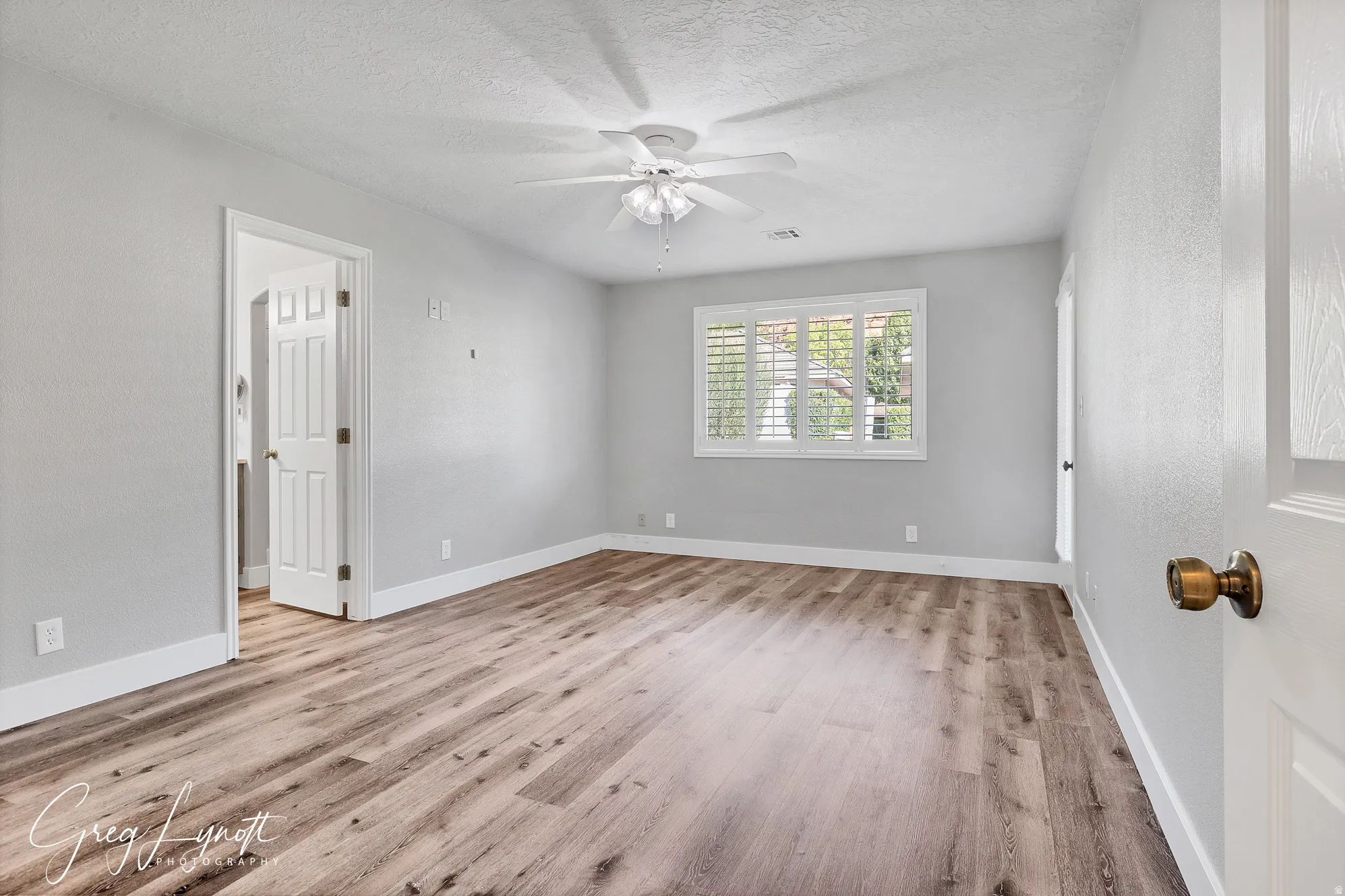 Spare room with light wood-style floors, a ceiling fan, and a textured ceiling