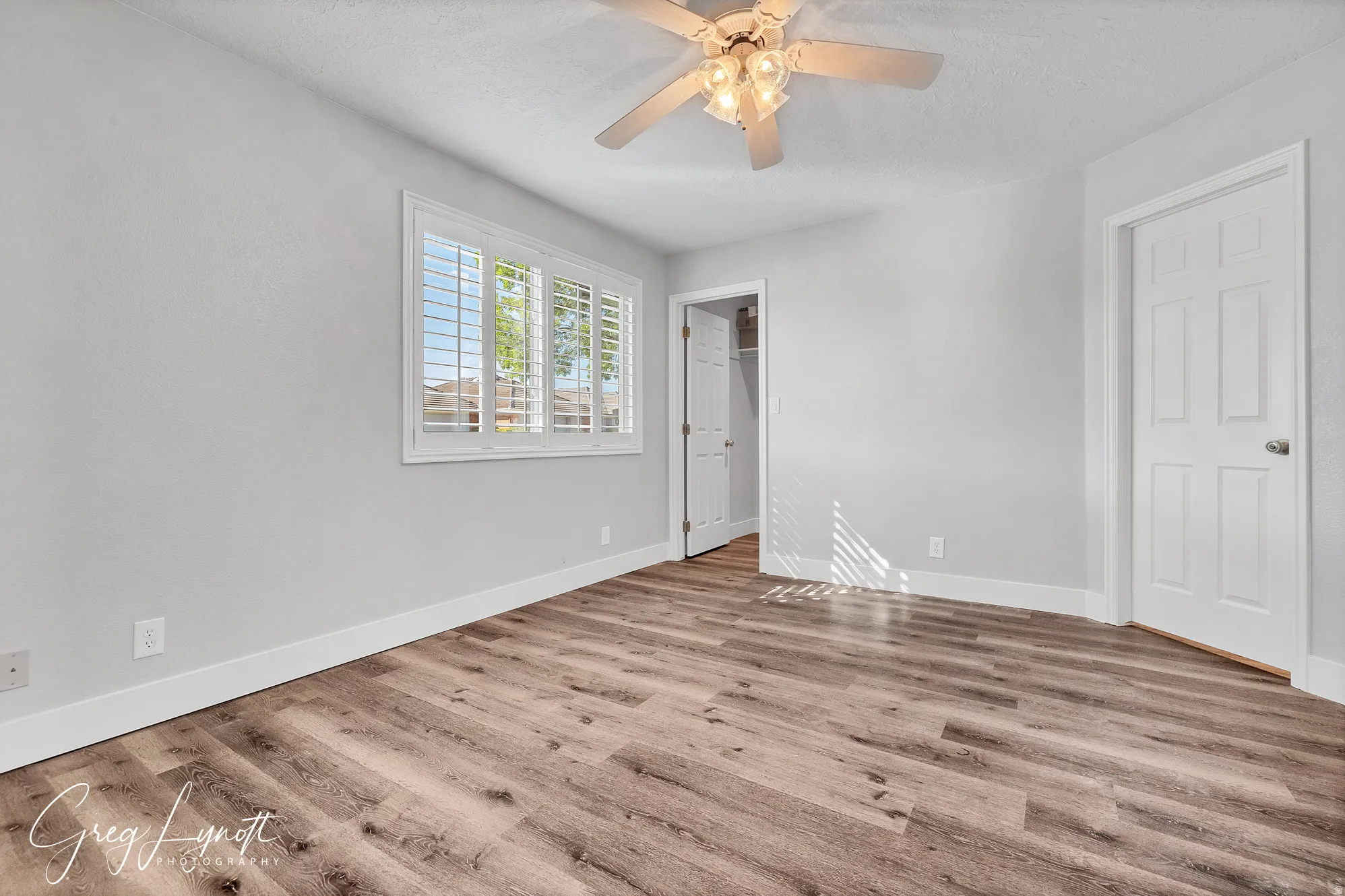 Unfurnished bedroom with a walk in closet, light wood-type flooring, and a ceiling fan
