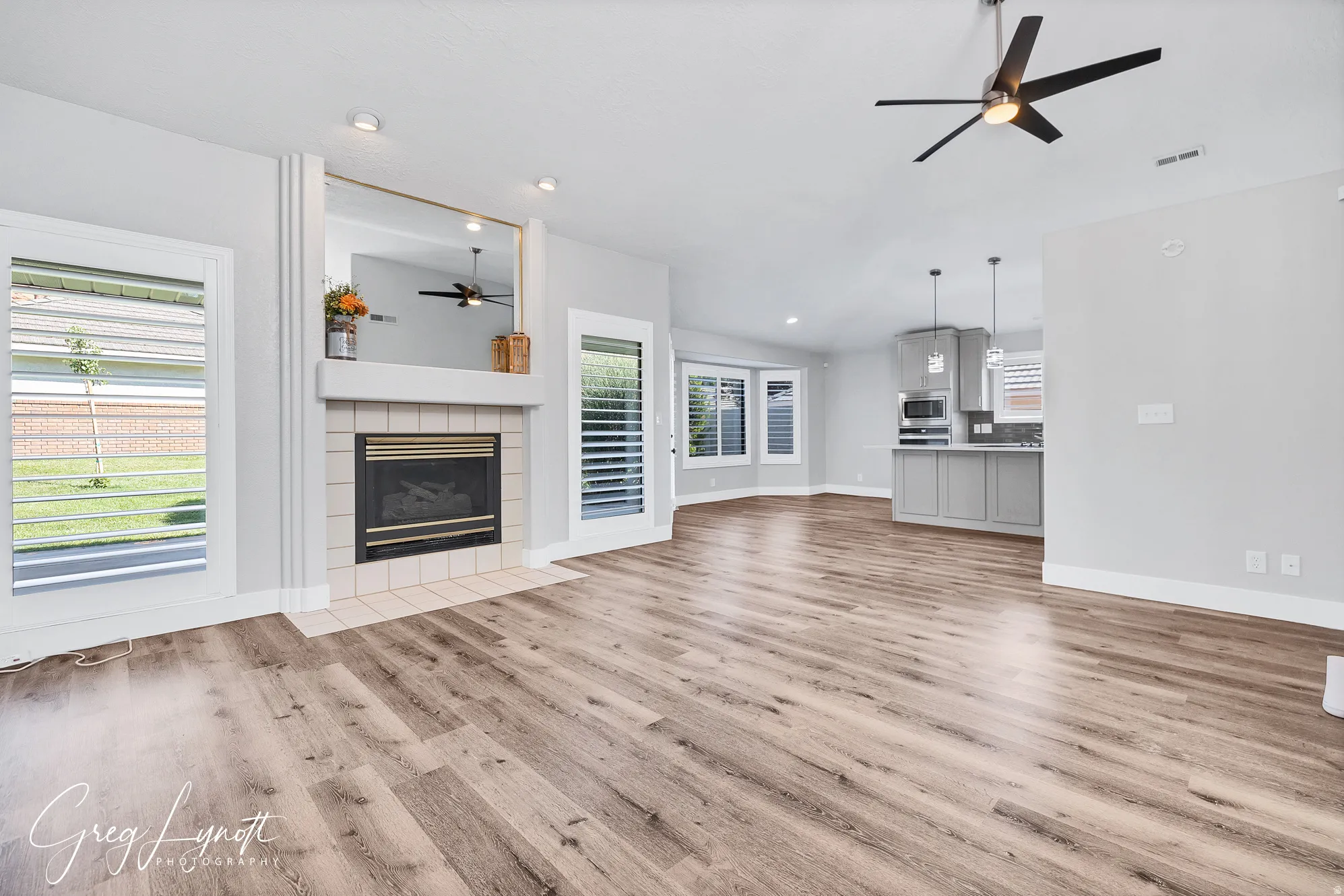Unfurnished living room with a ceiling fan, a tile fireplace, light wood finished floors, and recessed lighting
