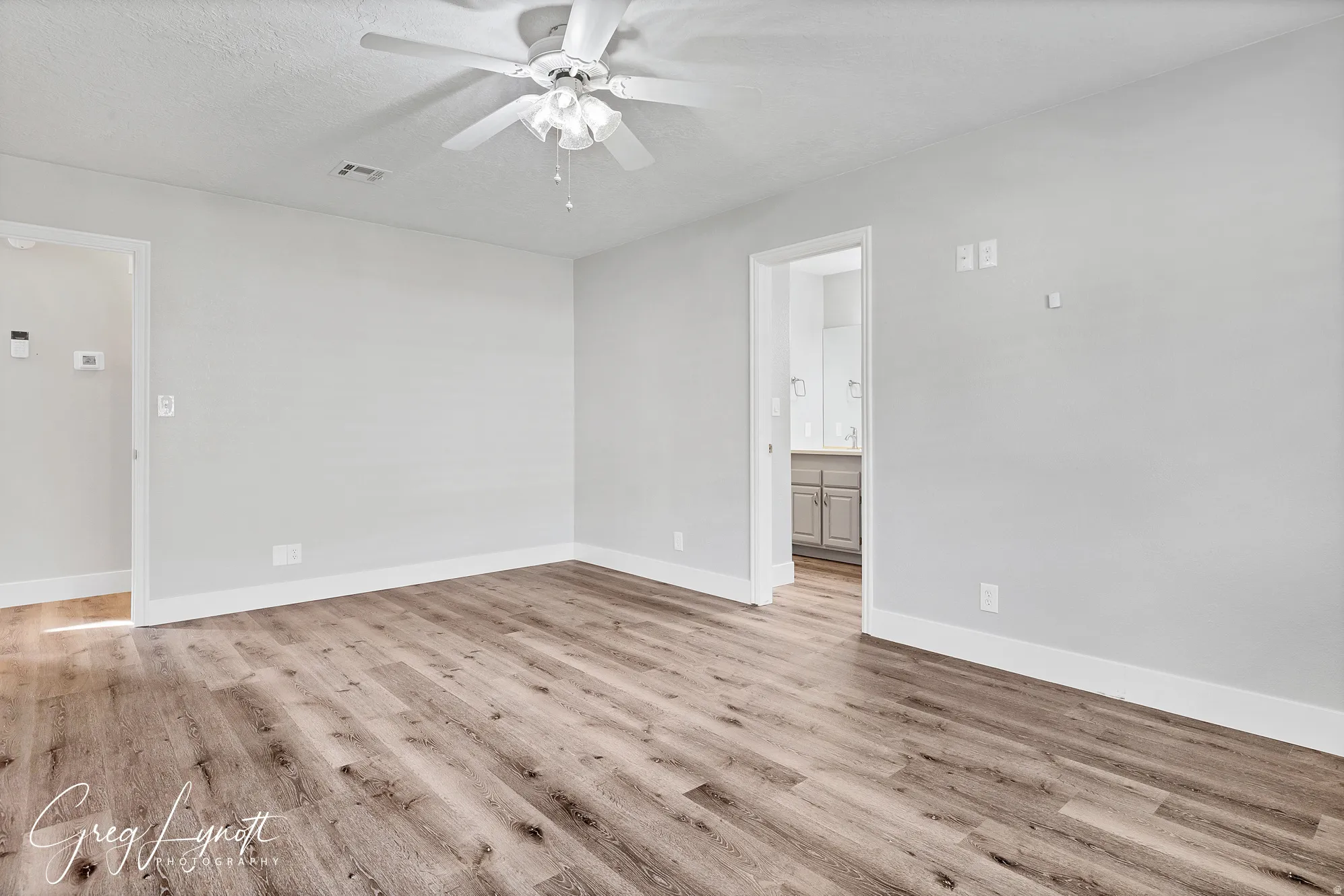 Unfurnished room featuring ceiling fan, light wood-type flooring, and a textured ceiling