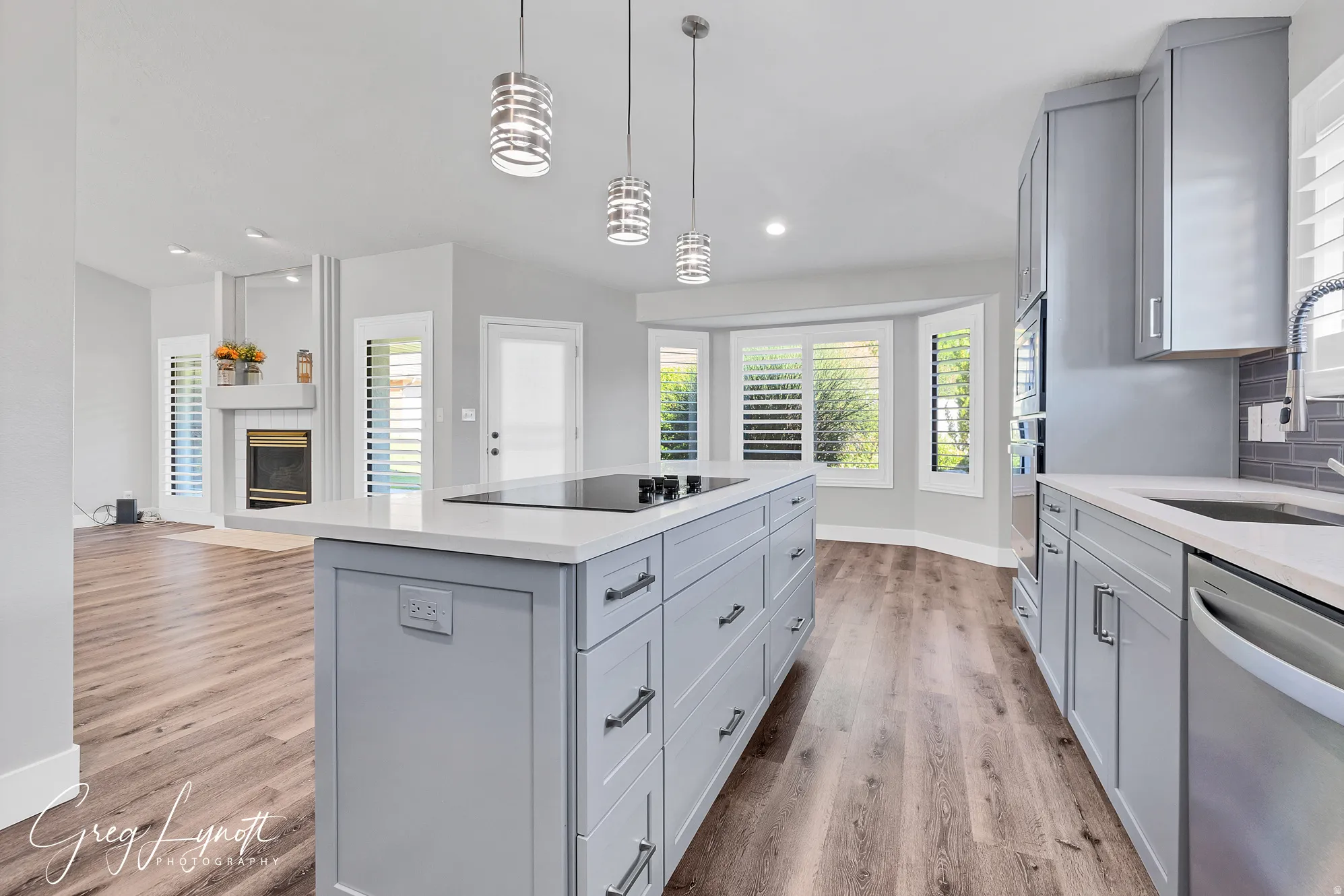 Kitchen featuring gray cabinets, stainless steel appliances, light stone counters, and pendant lighting