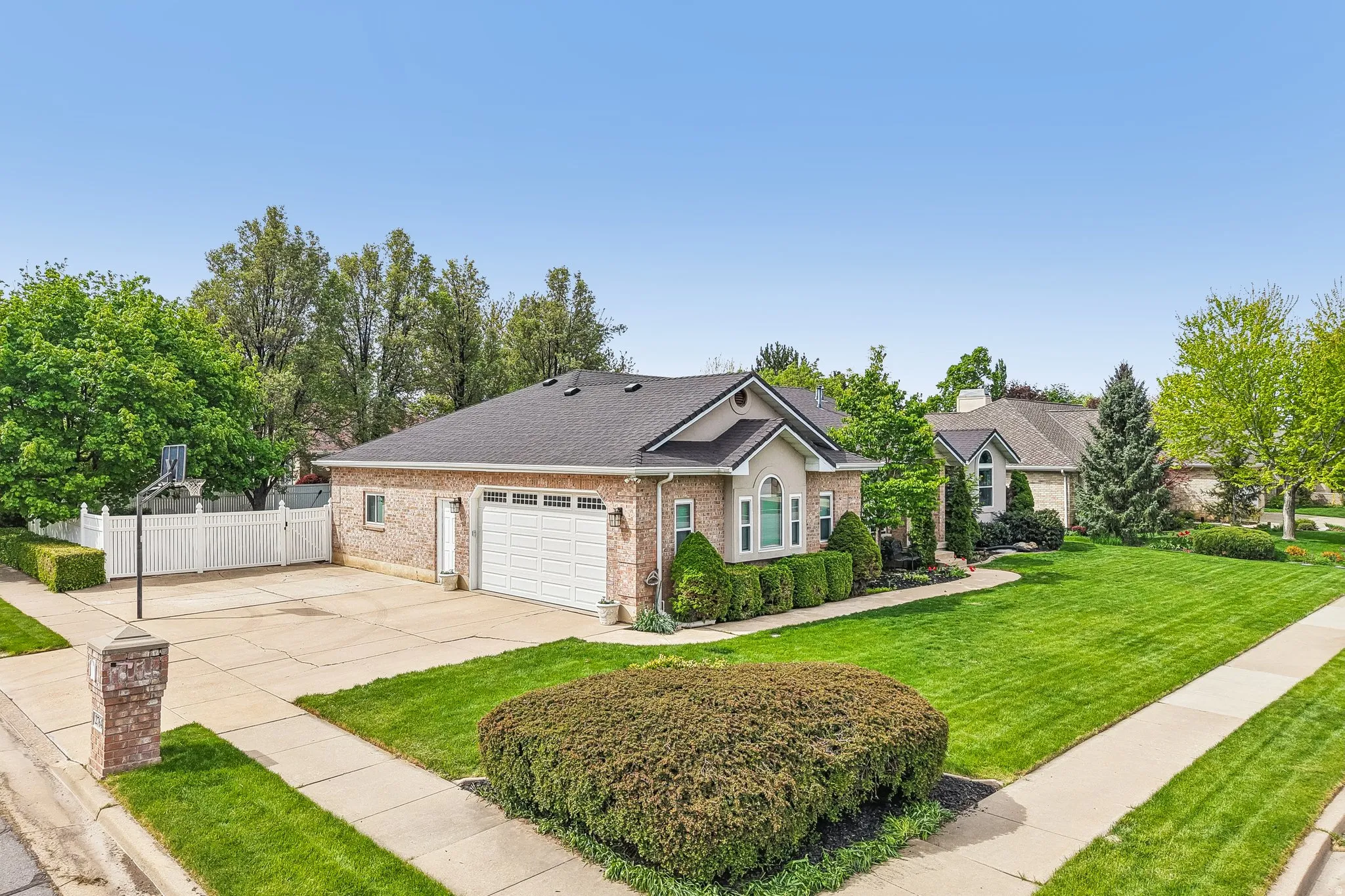Ranch-style house with concrete driveway, roof with shingles, brick siding, and a garage