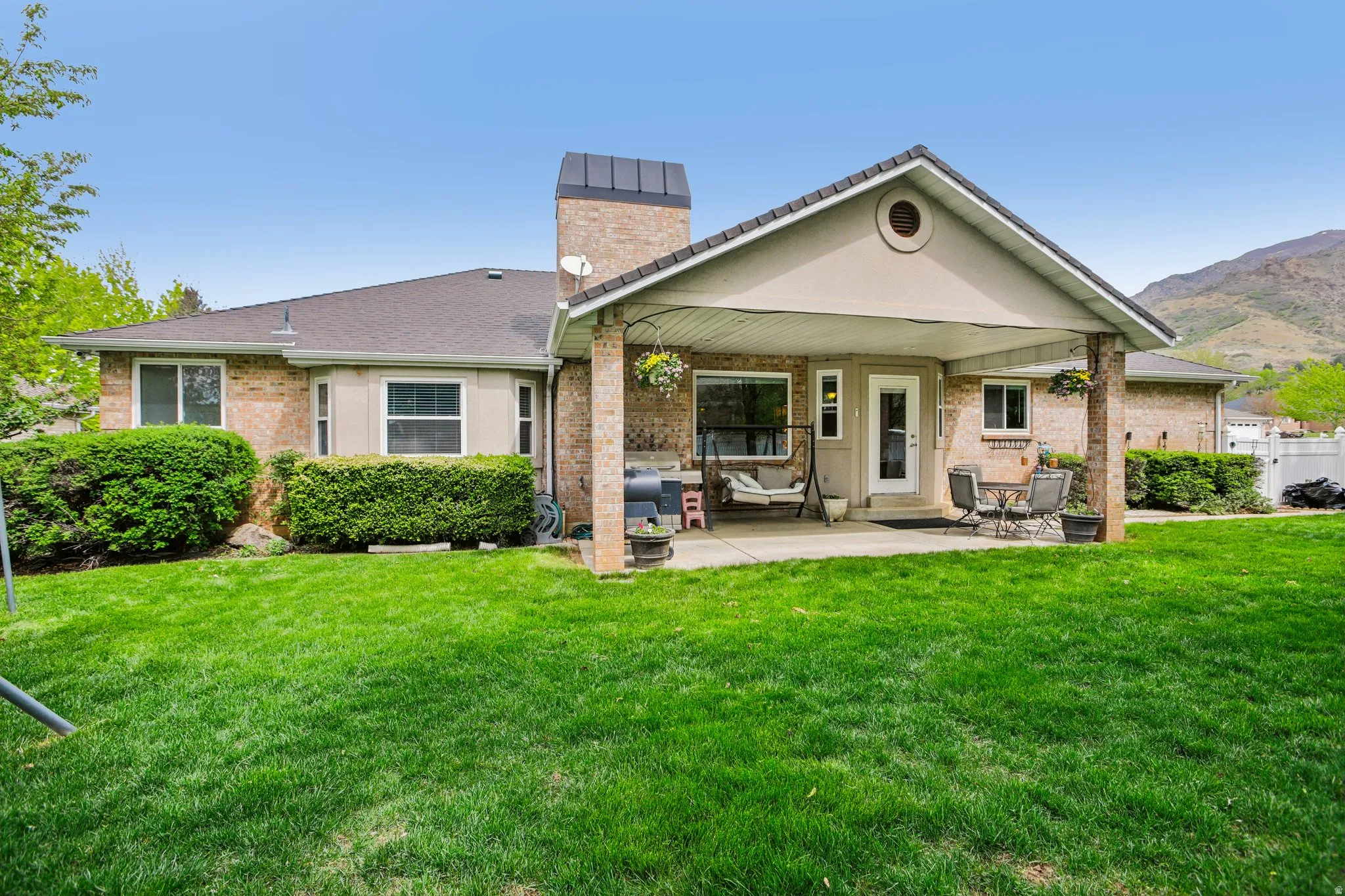 Rear view of house with a patio area, brick siding, a chimney, and a mountain view