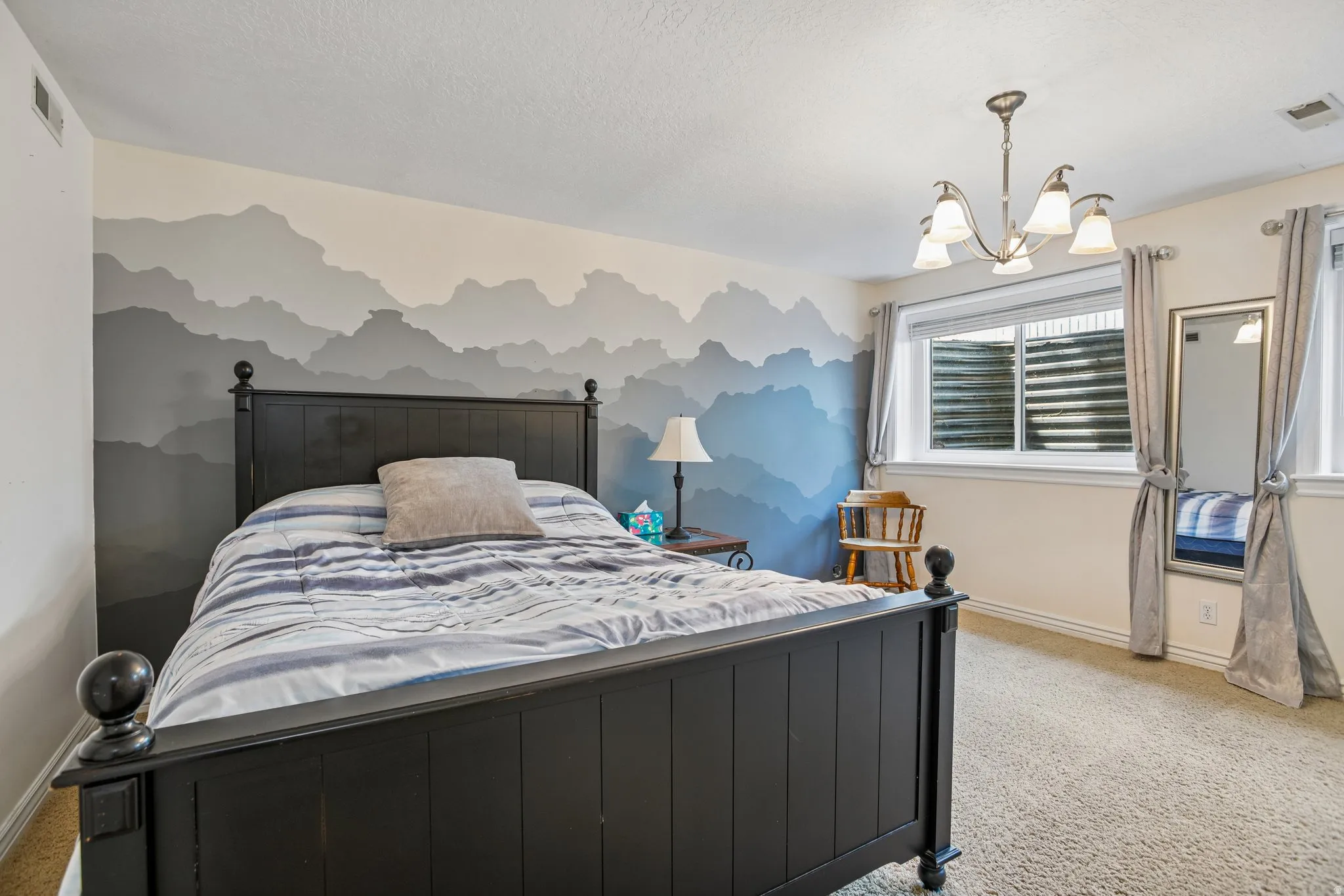 Bedroom with suspended lighting, light carpet, and a textured ceiling