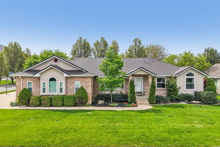 Single story home with brick siding, a front lawn, a shingled roof, and stucco siding