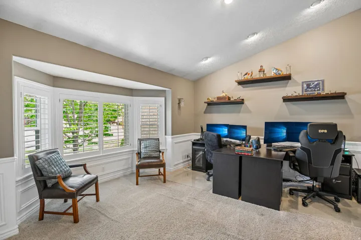 Office space featuring a decorative wall, wainscoting, and light colored carpet