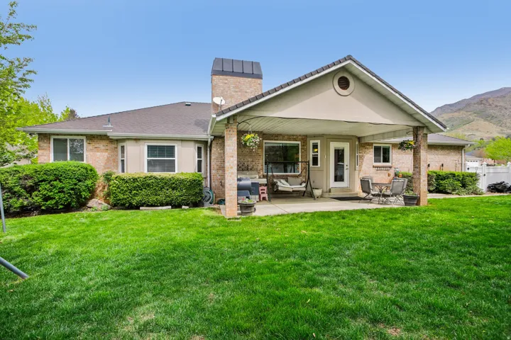 Rear view of house with a patio area, brick siding, a chimney, and a mountain view