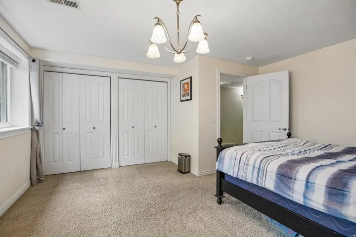 Bedroom with two closets, light carpet, a chandelier, and a textured ceiling