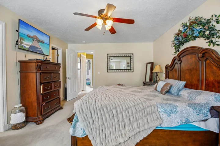 Bedroom featuring ceiling fan, a textured ceiling, and light carpet