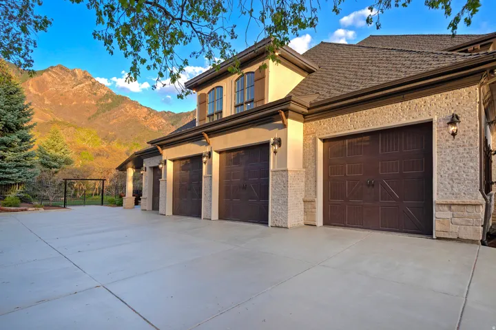 View of front of home with stucco siding, driveway, a mountain view, and stone siding