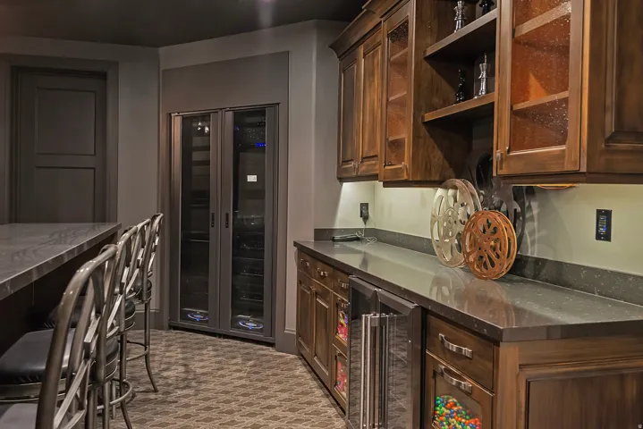 Kitchen featuring beverage cooler, dark stone counters, glass insert cabinets, and dark wood finish cabinetry