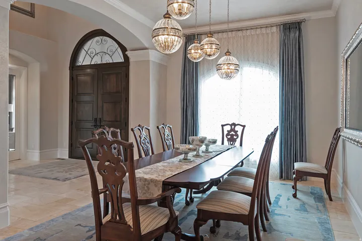 Dining area with arched walkways, suspended lighting, ornamental molding, and stone tile floors