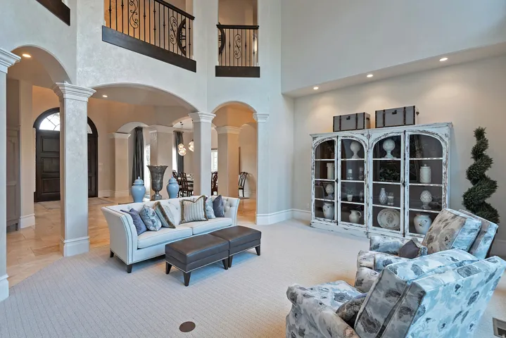 Living room featuring arched walkways, decorative columns, light carpet, a high ceiling, and recessed lighting