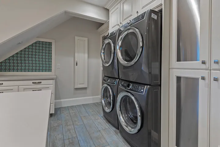 Laundry room with cabinet space, light wood-type flooring, and vaulted ceiling