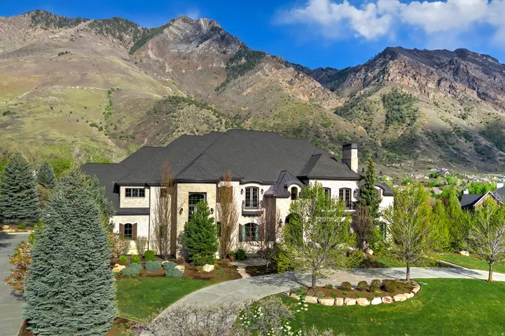 View of front of property with a mountain view, a front yard, a chimney, and stone siding