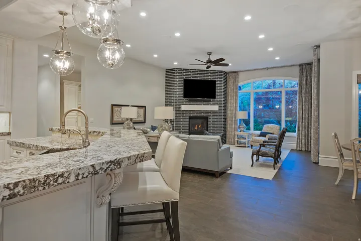 Kitchen with light stone counters, dark wood finished floors, a kitchen breakfast bar, pendant lighting, and a fireplace