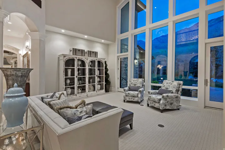 Carpeted living area with a high ceiling, arched walkways, ornate columns, recessed lighting, and expansive windows