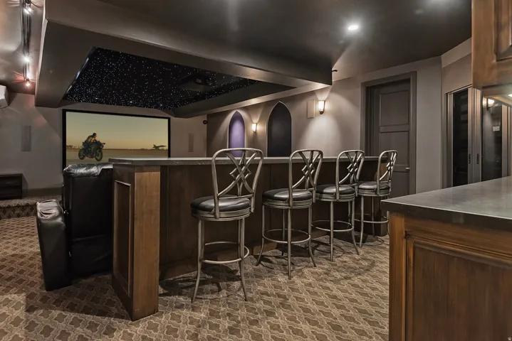 Home theater room featuring dark carpet and a community bar